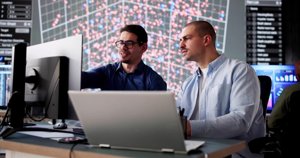 Collaborateurs analysant des données sur écrans informatiques dans un environnement technologique, illustrant les métiers IT, l’infrastructure et le développement des systèmes d’information - OCEA Smart Building