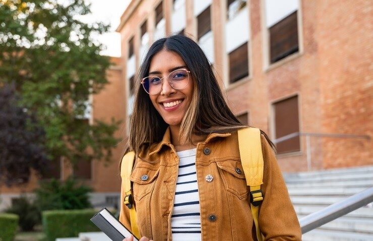 Étudiant en alternance devant un bâtiment professionnel, avec sac à dos et ordinateur, illustrant le parcours d’apprentissage en entreprise chez OCEA Smart Building