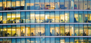 Immeuble de bureaux moderne avec espaces de travail visibles à travers la façade vitrée, illustrant le pilotage des consommations d’énergie et l’optimisation des charges dans les bâtiments tertiaires – OCEA Smart Building – Groupe OCEA