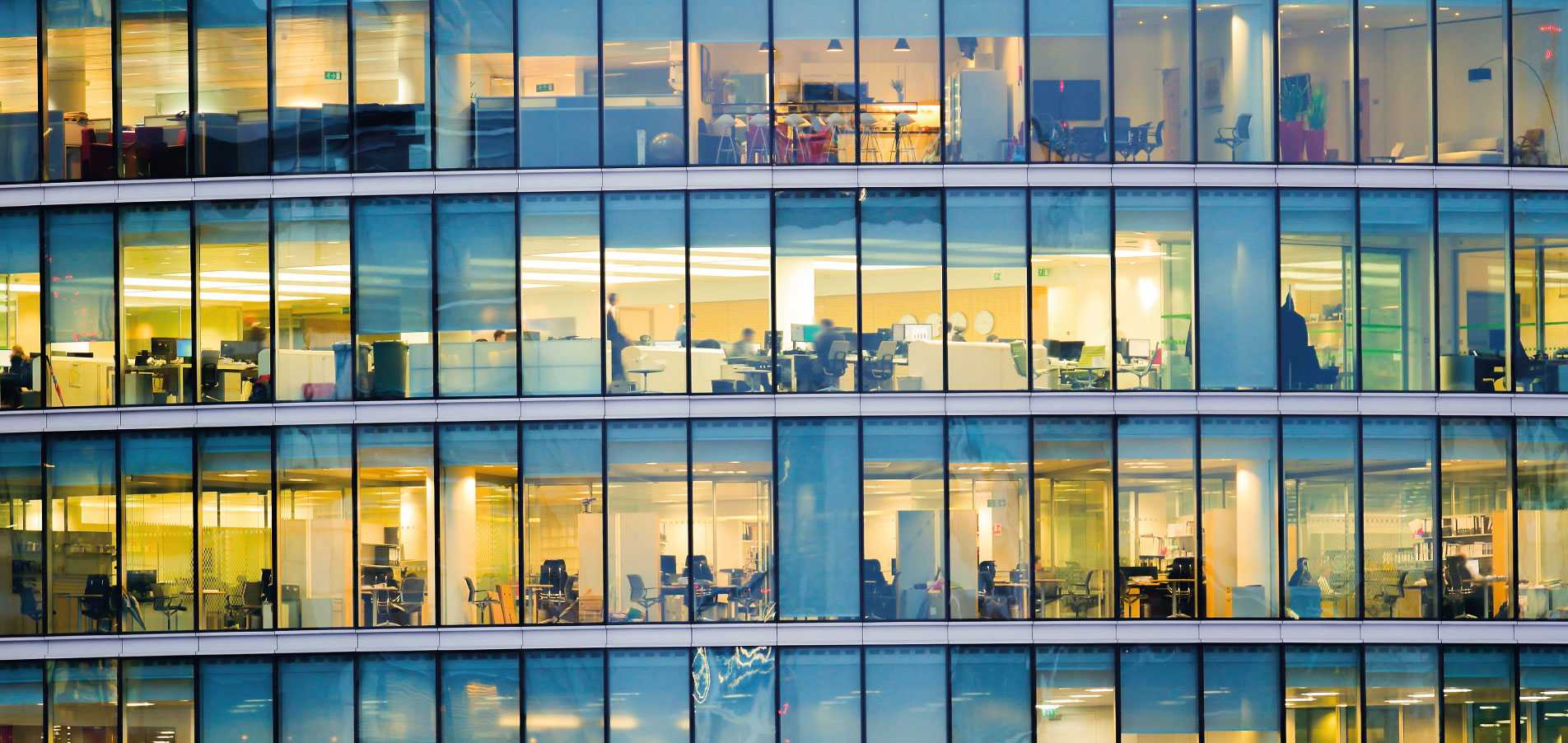 Immeuble de bureaux moderne avec espaces de travail visibles à travers la façade vitrée, illustrant le pilotage des consommations d’énergie et l’optimisation des charges dans les bâtiments tertiaires – OCEA Smart Building – Groupe OCEA