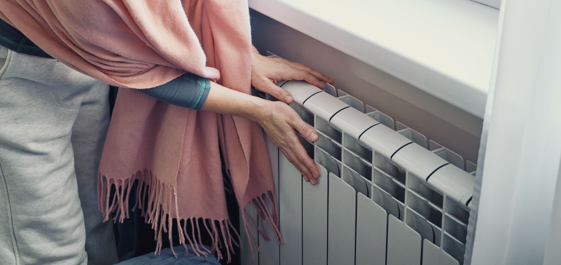 Copropriétaire ou occupant ajustant un radiateur intérieur, illustrant la maîtrise de la consommation de chauffage, le confort thermique et la réduction des charges énergétiques dans le logement - OCEA Smart Building - individualisation des frais de chauffage