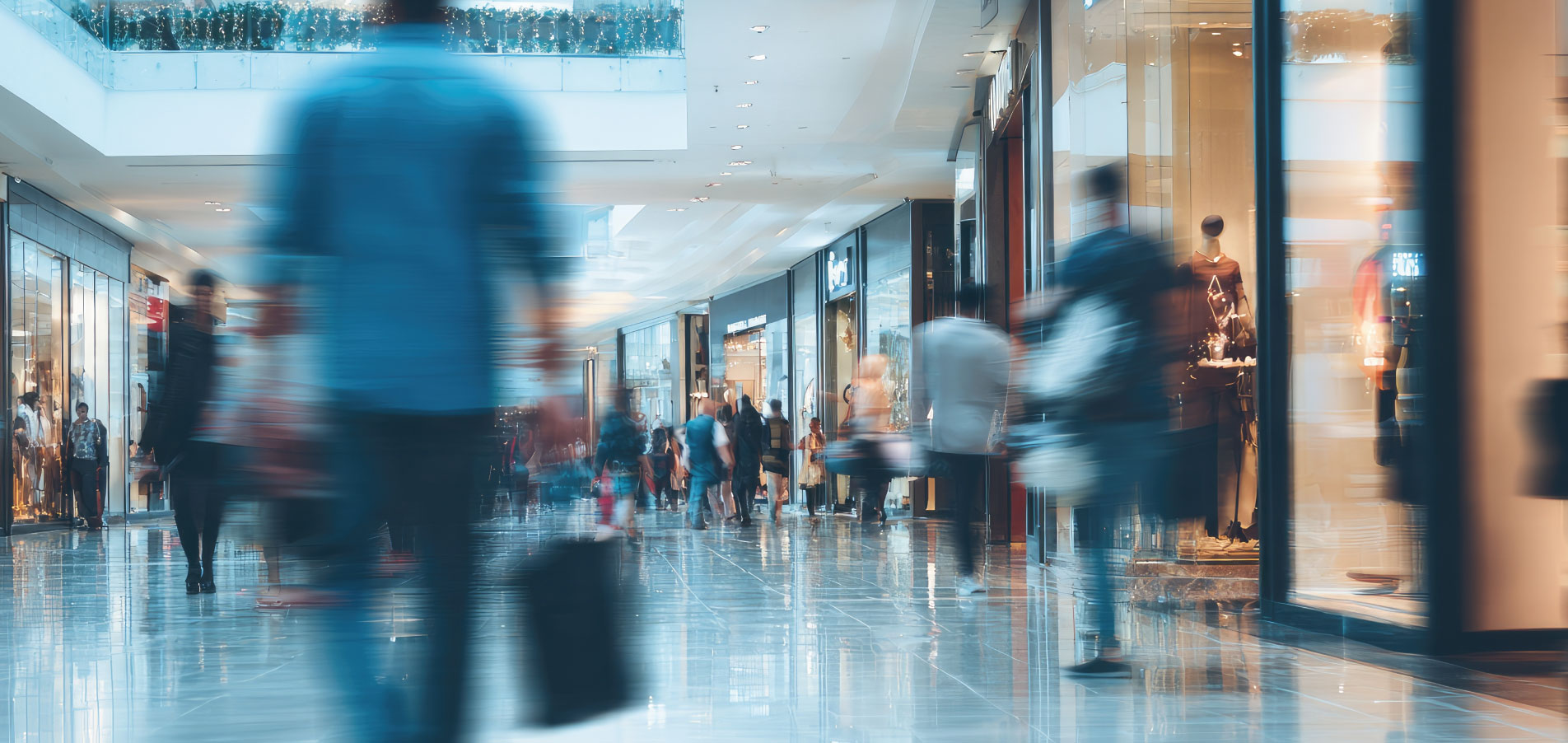 Centre commercial animé avec escalators et visiteurs en mouvement, illustrant la gestion des flux, la maîtrise des consommations d’énergie et l’optimisation des charges dans l’immobilier commercial – OCEA Smart Building – Groupe OCEA