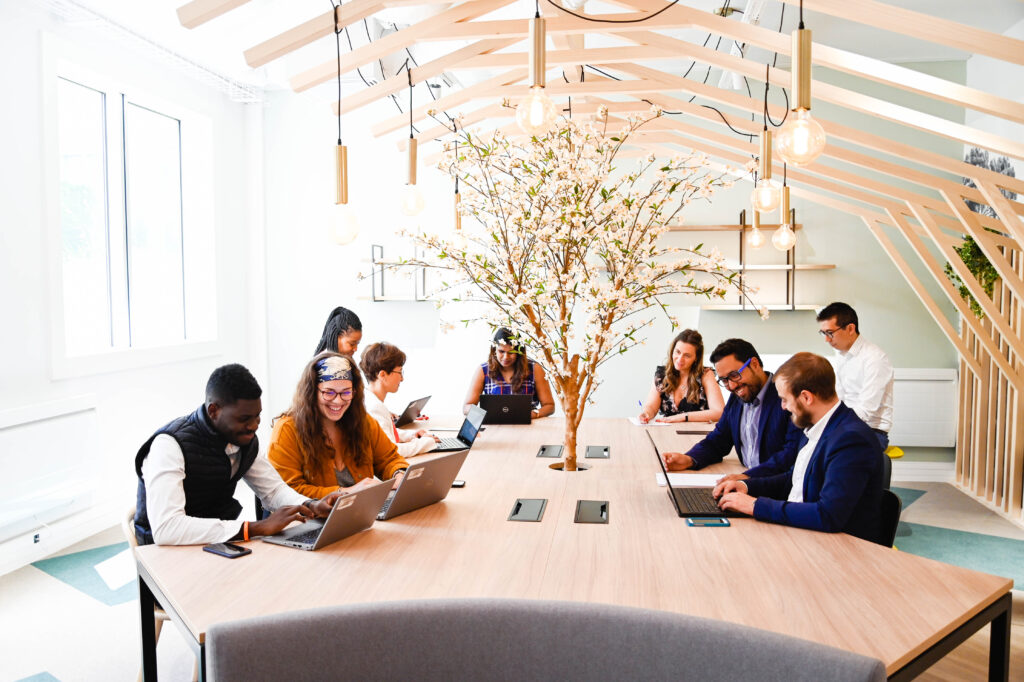 Équipe de collaborateurs réunis autour d’une table de travail dans un espace lumineux et moderne, illustrant la collaboration, la qualité de vie au travail et le développement des compétences en entreprise - OCEA Smart Building