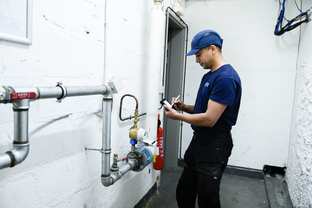 Technicien OCEA réalisant un relevé technique sur une installation de bâtiment avec un outil numérique